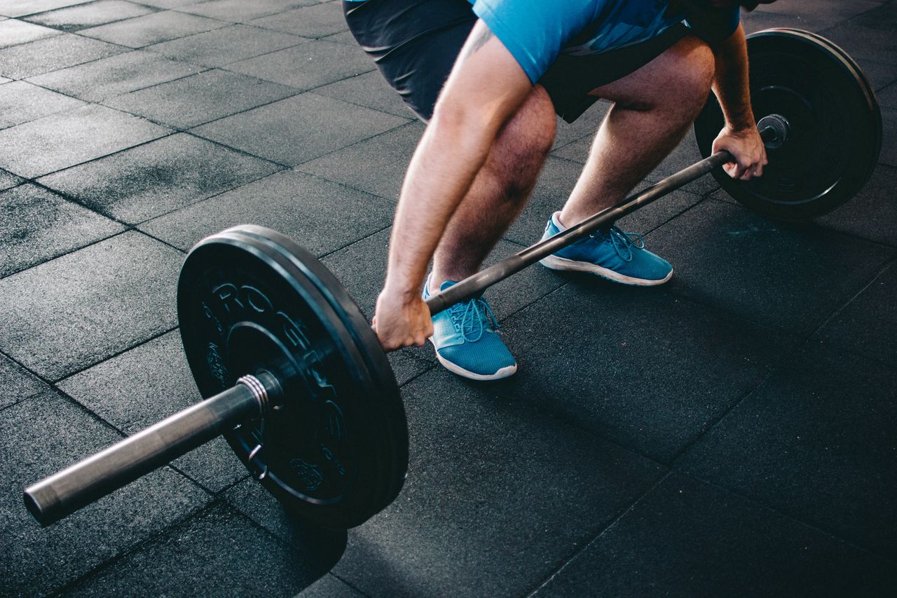 A man deadlifting a barbell indoors showcasing power, fitness, and dedication.